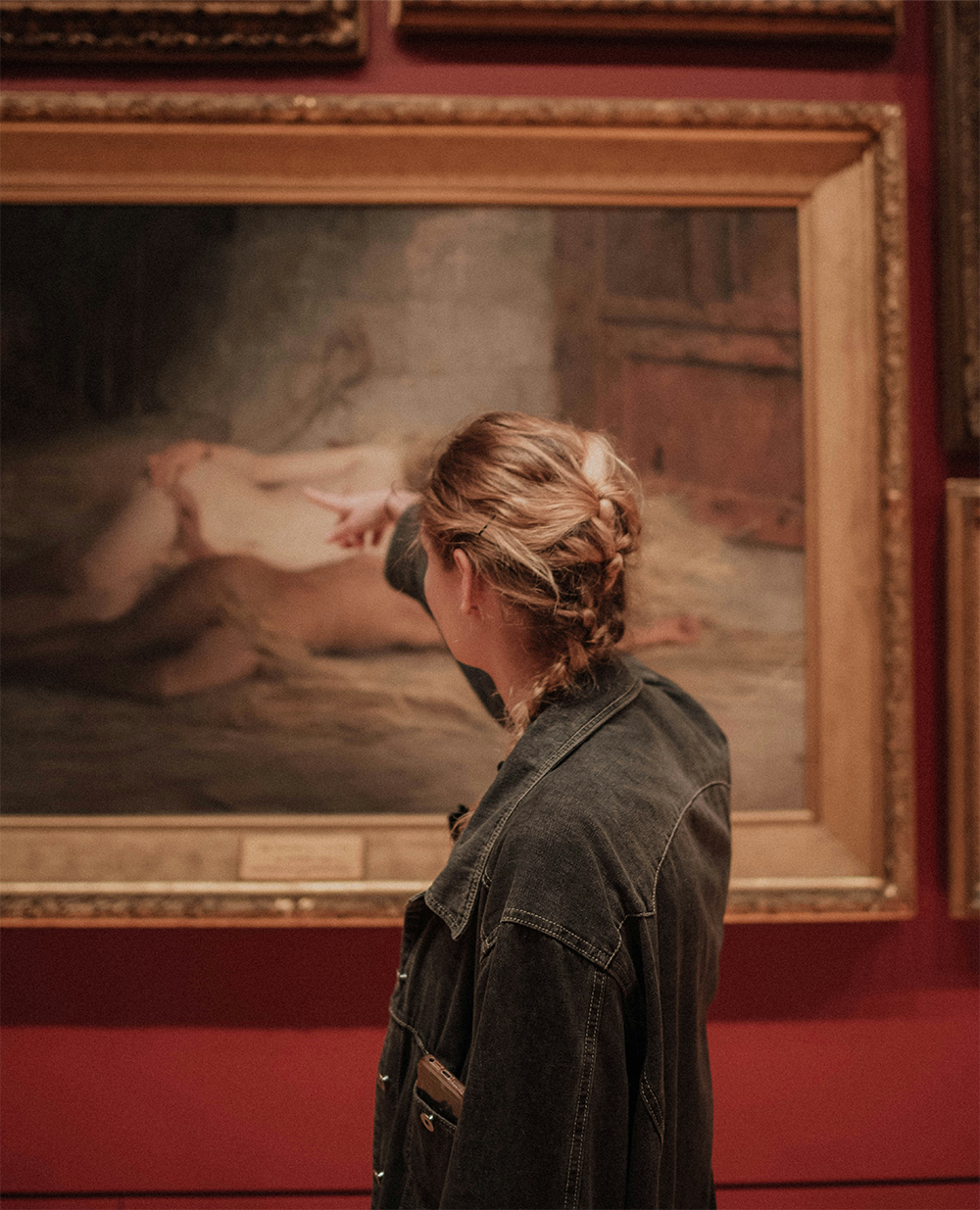 Museum visitor pointing at artwork in a red gallery