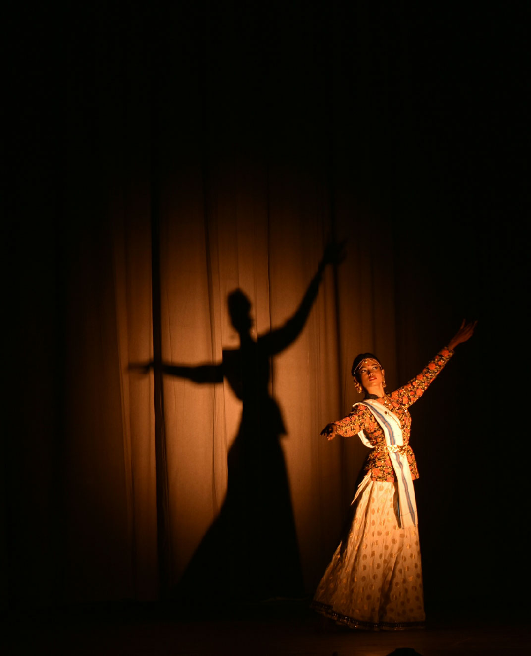 An actor performs on stage under a spotlight